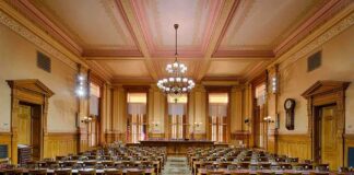 Interior view of a historic courtroom with wooden furnishings and chandeliers