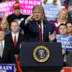Trump’s Dual Memorial Day Message Shocks Nation Person speaking at rally with crowd behind podium
