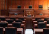 Empty courtroom with wooden benches and judges bench.