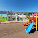 Two Shooters GUN DOWN Children’s Playground! Colorful playground slide in front of a building.
