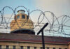 Female Prison Guard ARRESTED – Shocking Rape Claims! Barbed wire in front of a prison tower.