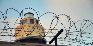 Female Prison Guard ARRESTED – Shocking Rape Claims! Barbed wire in front of a prison tower.