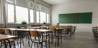 Teacher Fired Over Kissing Skits – Back In The Classroom Empty classroom with desks, chairs, windows, and chalkboard.