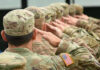 Soldiers in uniform saluting, American flag patch visible.