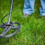 A metal detector being used on grassy ground