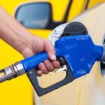 Gas Price SKYROCKETS Amid 250th Celebrations! A person refueling a car at a gas station with a blue nozzle