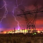 Midwest Blackout Triggers Airport Chaos Lightning strikes illuminate a power station against a colorful sunset sky