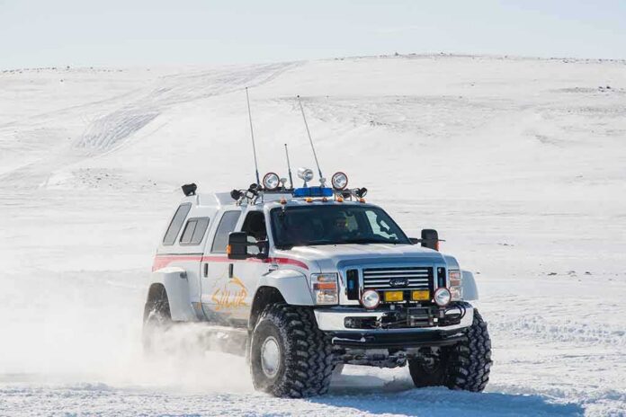 Lifted white expedition truck driving through snowy terrain