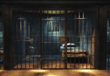 Prison cell with metal bars and a single bed