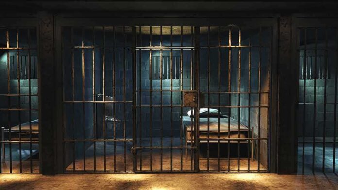 shutterstock_1427252378 Prison cell with metal bars and a single bed