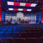 Debate stage with red and blue lighting and empty audience seats