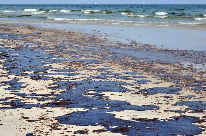 shutterstock_55817806 Oil spill on a sandy beach with waves in the background