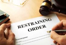 Restraining order form on a desk with hands holding a pen
