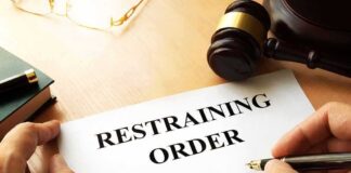 GOP Rep’s Wife Files Restraining Order After Disturbing Allegations Restraining order form on a desk with hands holding a pen