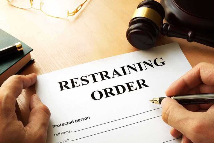 Restraining order form on a desk with hands holding a pen