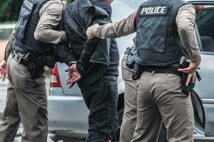 shutterstock_1137889661 Police officers arresting a person beside a car