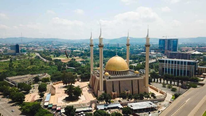 shutterstock_1439453054 Golden-domed mosque with four minarets in a modern cityscape