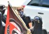 Masked protesters holding a black and red flag