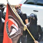 Antifa Mob ATTACKS Conservative Star in Church Masked protesters holding a black and red flag