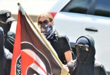 Masked protesters holding a black and red flag