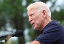 Biden Aide VANISHES After Endorsing Republican elderly man speaking into a microphone outdoors