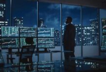 Business Growth Hits 52-Month High! Trader in a dark office with multiple stock monitors and city skyline at night