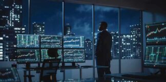 Business Growth Hits 52-Month High! Trader in a dark office with multiple stock monitors and city skyline at night