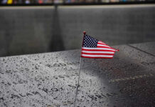 9/11 Families to Mayor: Stay Away American flag on a rainy memorial nameplate.