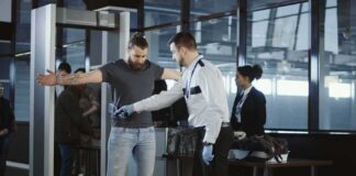 Airport security officer scanning a passenger with a handheld metal detector