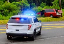 Dem Candidate ARRESTED – Handcuffed in Squad Car Police SUV with flashing lights at roadside crash scene
