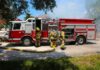 27 Students DEAD in Blazing School Inferno Fire truck with firefighters operating hoses on a residential street