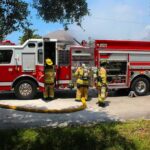 Fire truck with firefighters operating hoses on a residential street