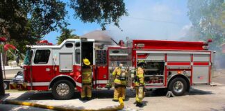 Fire truck with firefighters operating hoses on a residential street