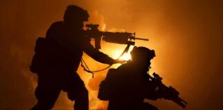 Two armed soldiers silhouetted against fiery smoke
