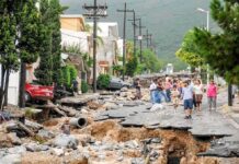 23 DEAD, Hundreds Missing After Deadly Flash Flood Residents walk along a heavily damaged street after a disaster