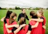 Stolen Medals Shock: Title IX Showdown Coach talks to youth team in a huddle on a field