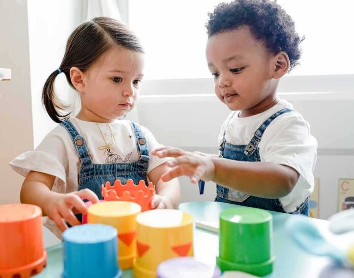 Toddlers playing with colorful stacking cups at a table