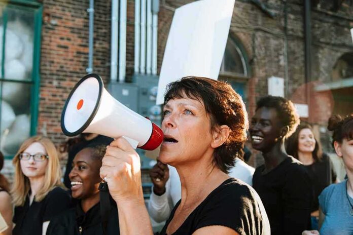 shutterstock_1250469094 Woman with megaphone leading a protest