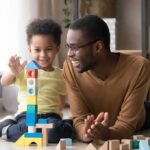 Airlines Providing a Huge Benefit to Flyers With Trump Accounts Father and child building a tall tower with colorful wooden blocks on the floor