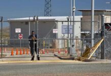 Air Base Breach Sparks Violent Clash Security guard at chain-link gate of fenced facility