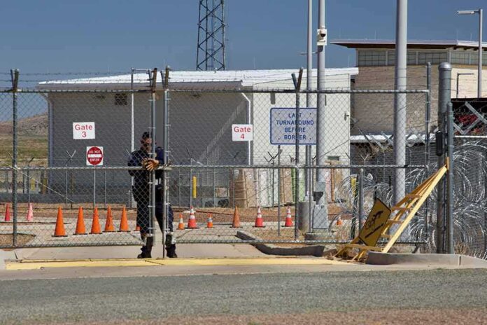 shutterstock_1383379523 Security guard at chain-link gate of fenced facility