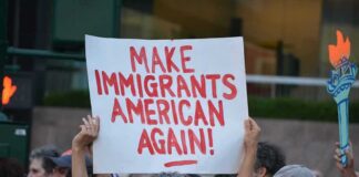 Teddy Williams at a protest holding a sign reading 'Make Immigrants American Again'