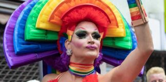 Drag performer in vibrant rainbow costume at a parade