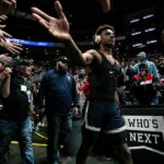 Basketball player in arena high-fives fans while wearing headphones