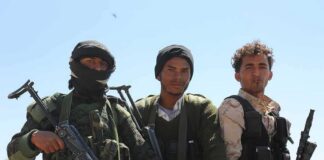 Three armed men standing outdoors