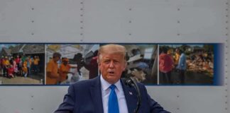 Donald Trump speaks at a podium with arms outstretched