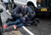 Powerball Winner ARRESTED Again For The Unthinkable Police officers restraining a person on a wet city street beside a truck