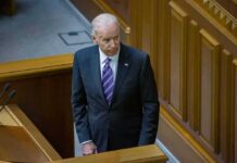 Joe Biden standing in a wood-paneled chamber in a dark suit