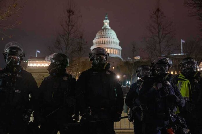 Riot police in protective gear stand before a domed capitol building at night