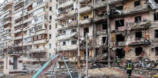 Damaged apartment building behind a playground slide
